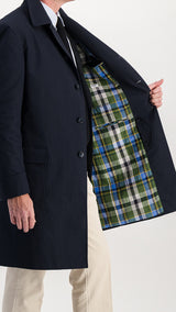 Le mannequin studio porte l'imperméable Alain en toile enduite coloris bleu marine de la collection Automne Hiver 2024 - vue de 3/4 côté, manteau ouvert avec détail de la doublure intérieure en Madras - de la Maison Gabriel Paris