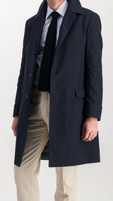 Le mannequin studio porte l'imperméable Alain en toile enduite coloris bleu marine de la collection Automne Hiver 2024 - vue de 3/4 côté, manteau ouvert - de la Maison Gabriel Paris